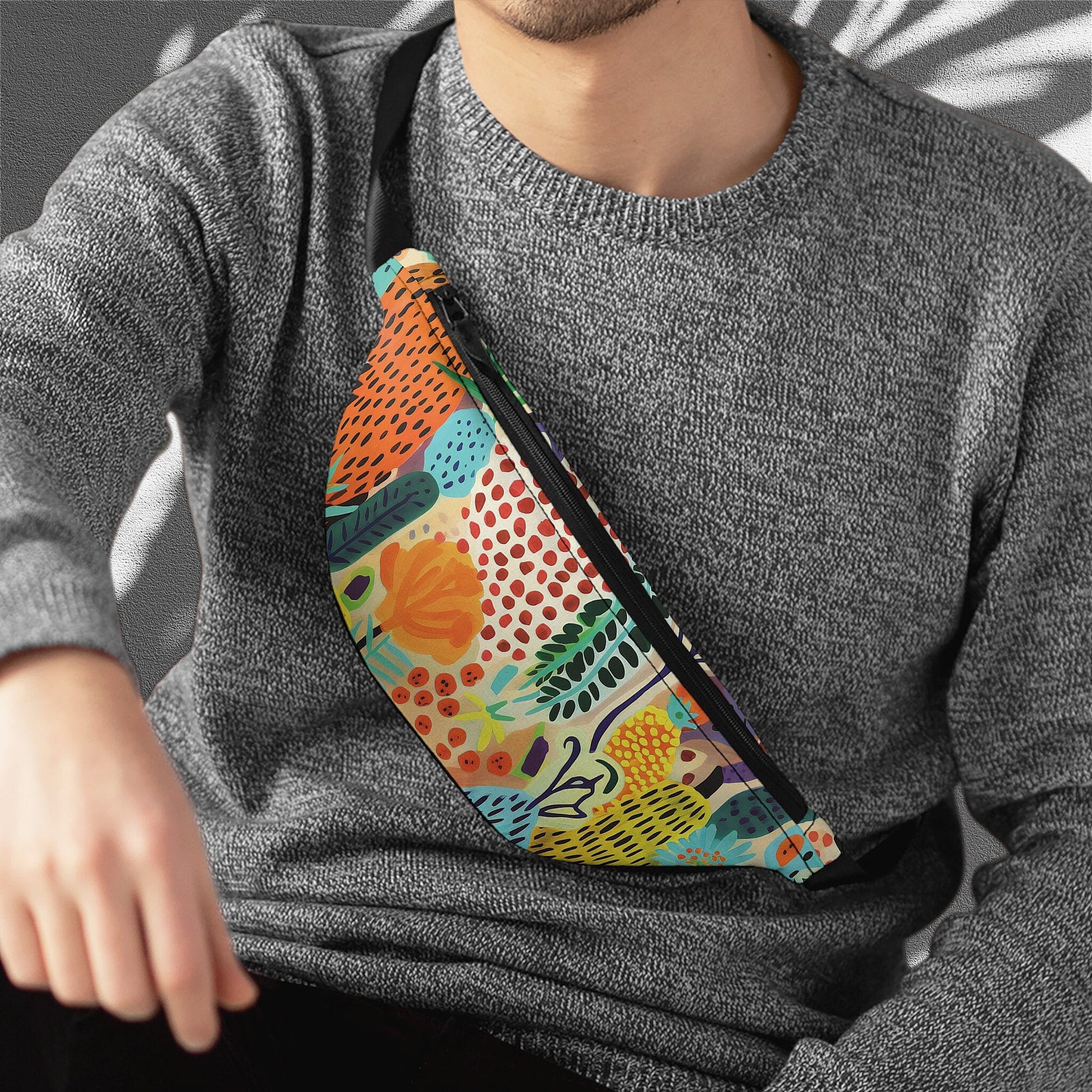 a man wearing a gray sweater and a colorful fanny bag