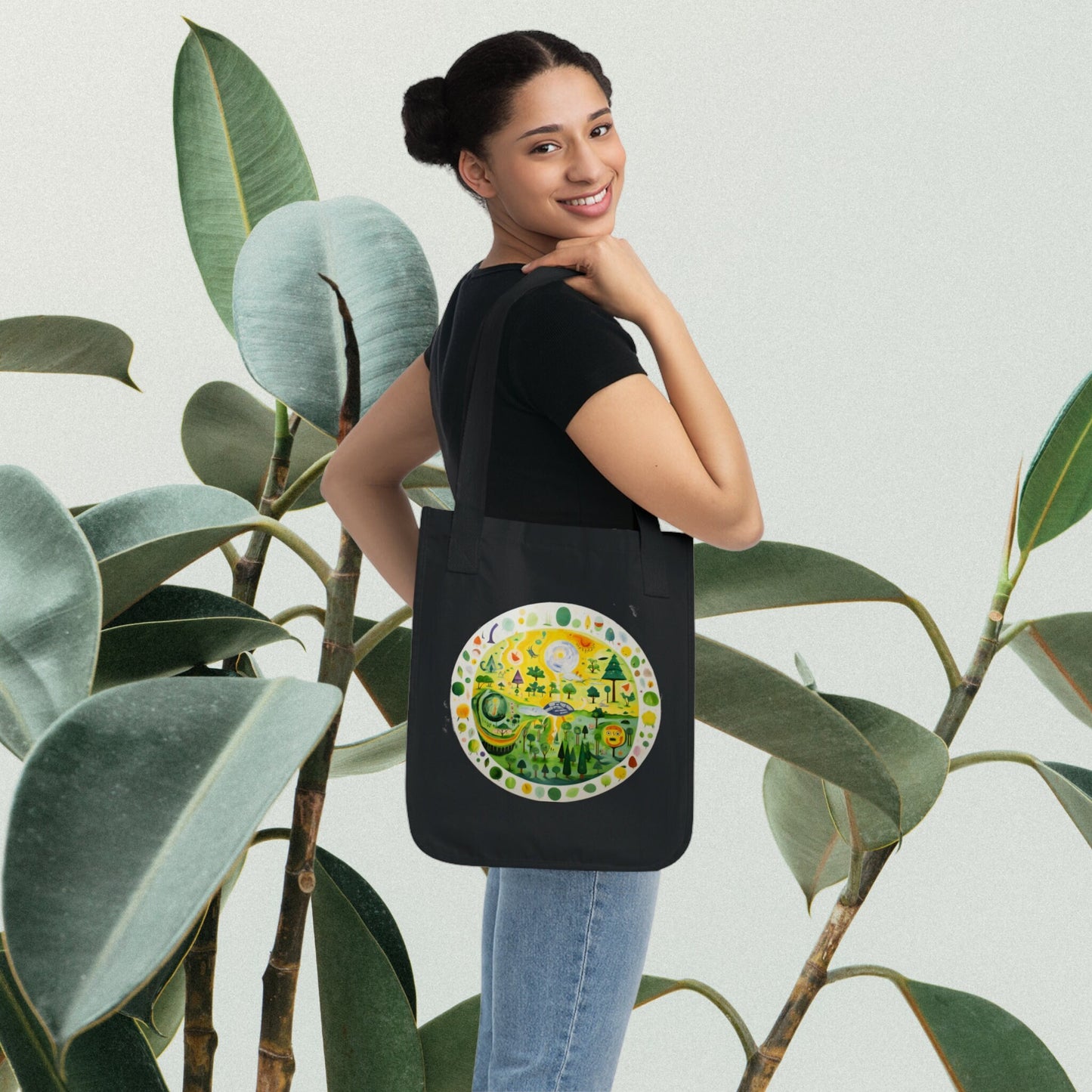 a woman holding a black tote bag in front of a plant
